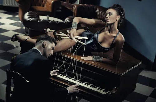 woman having fun by playing with her man's hands on a piano